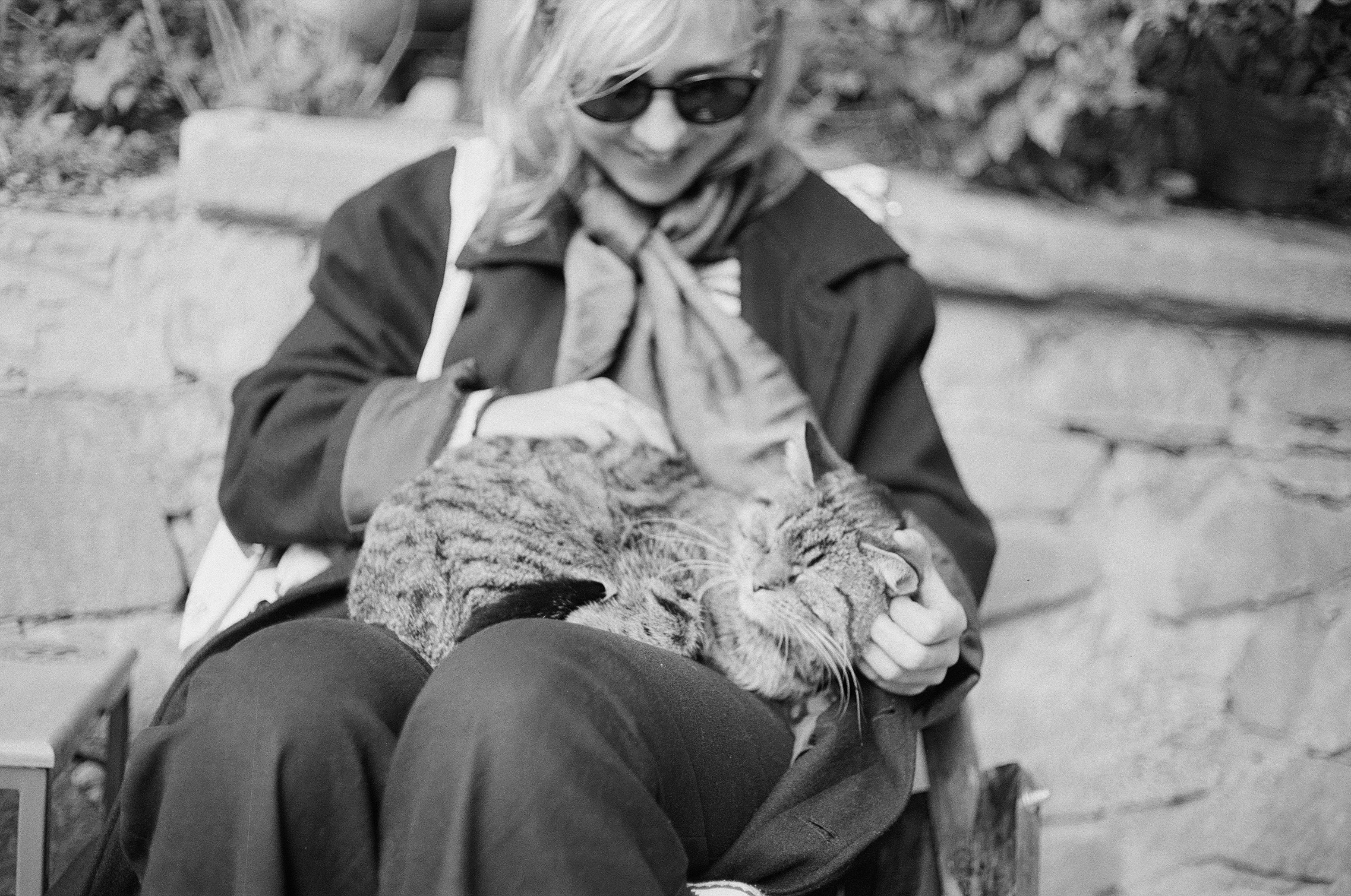 woman in black jacket and black pants wearing sunglasses sitting on bench